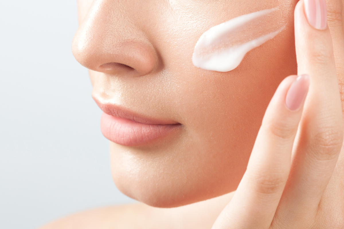closeup of woman's face as she applies spf to her cheek