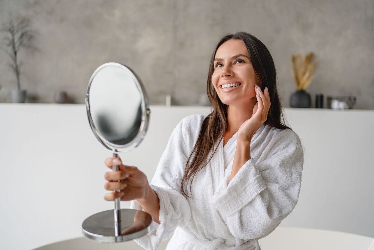 woman holding a mirror, smiling