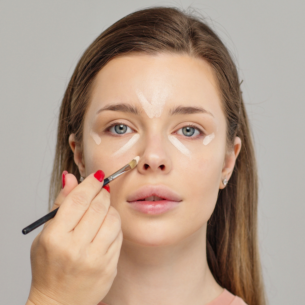 a woman applying concealer with a makeup brush