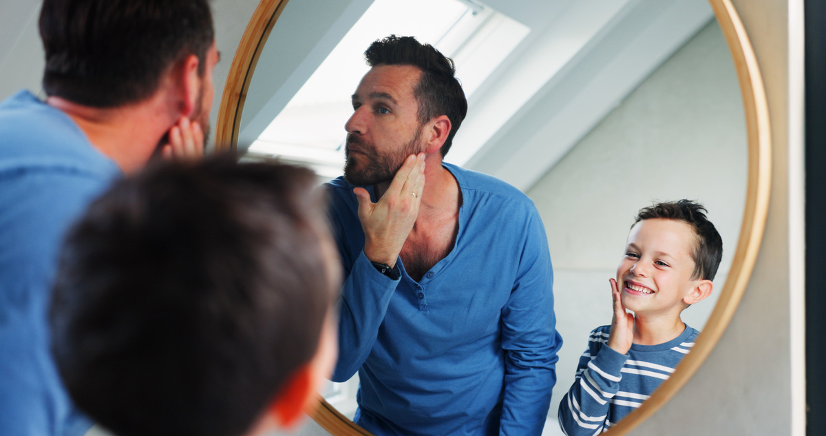 father and son looking at their skin in a mirror