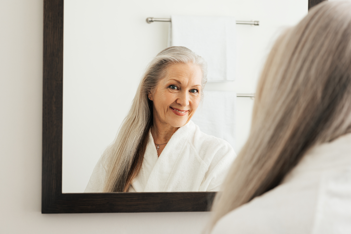 older woman smiling looking into mirror
